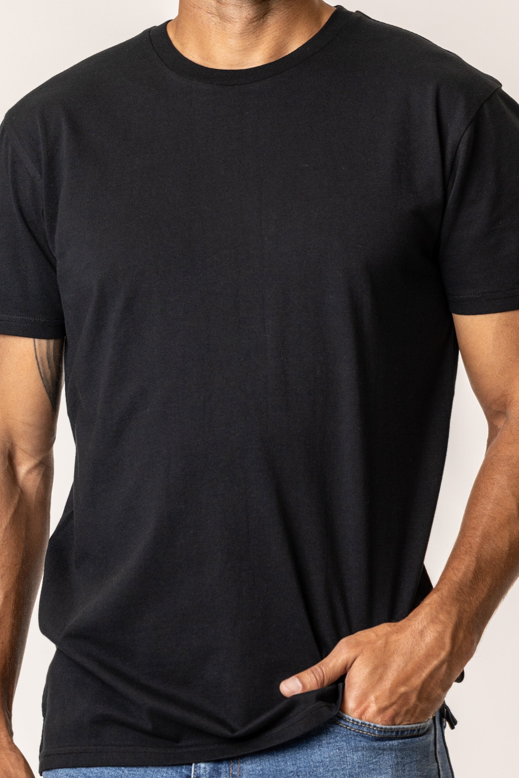 Person wearing a plain black t-shirt made of organic cotton