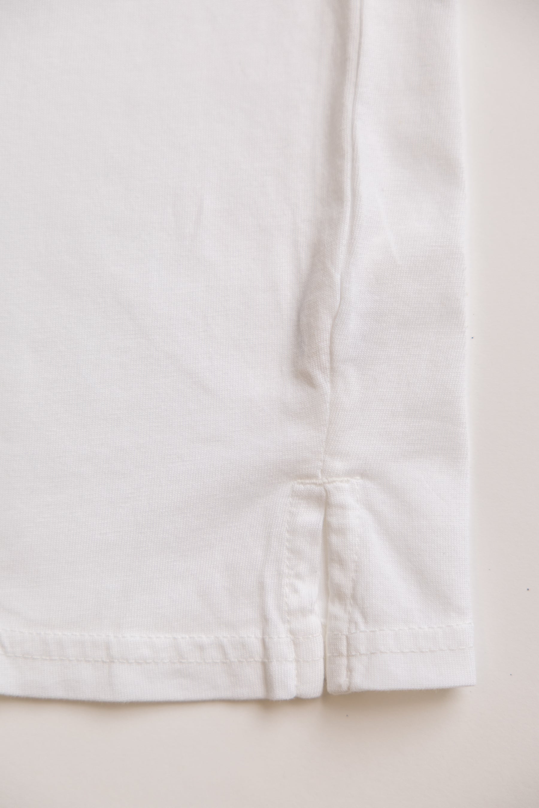 Close-up of a white organic cotton t-shirt fabric with a visible seam on a light background