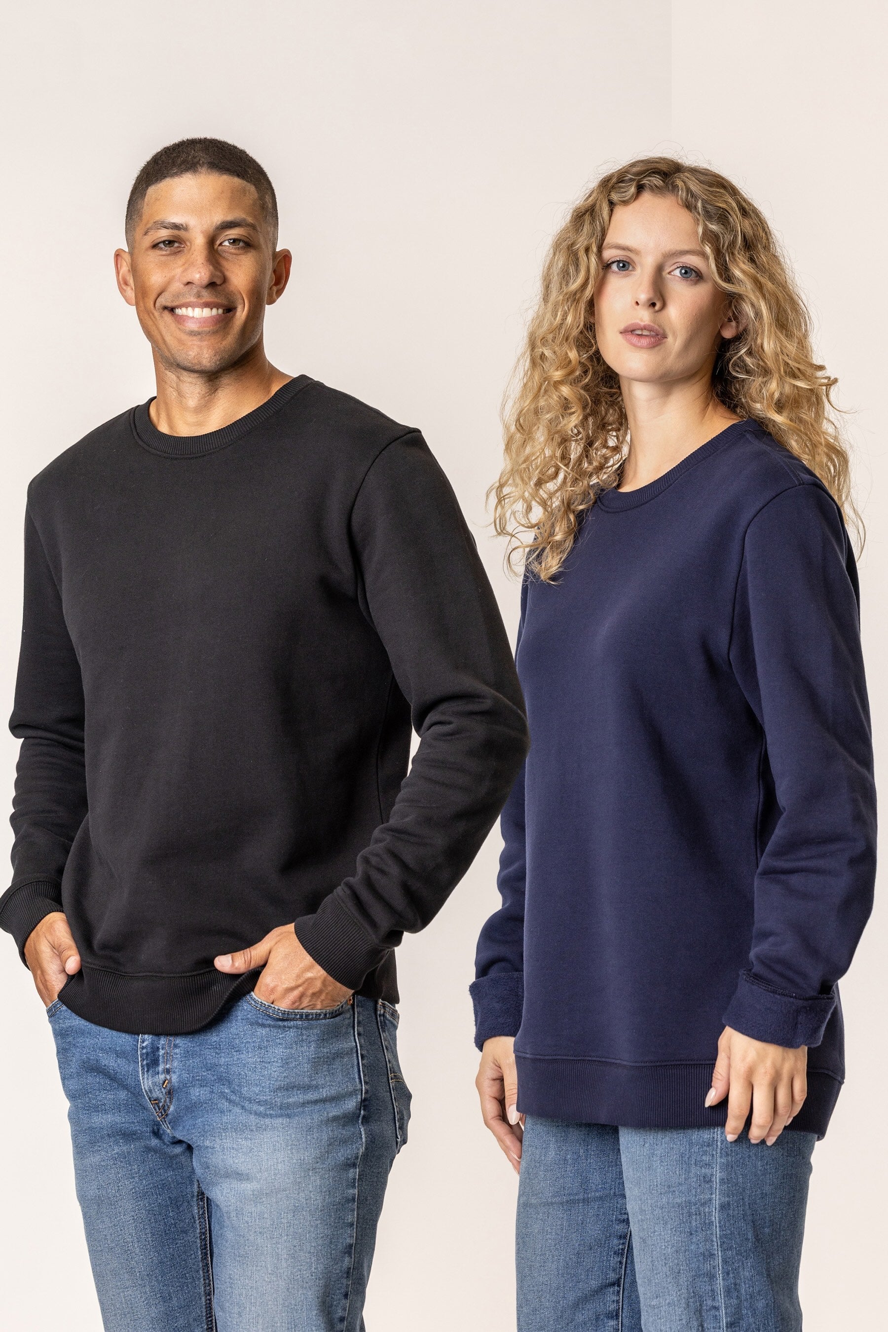 Man and woman wearing black and navy sweatshirts against a plain background