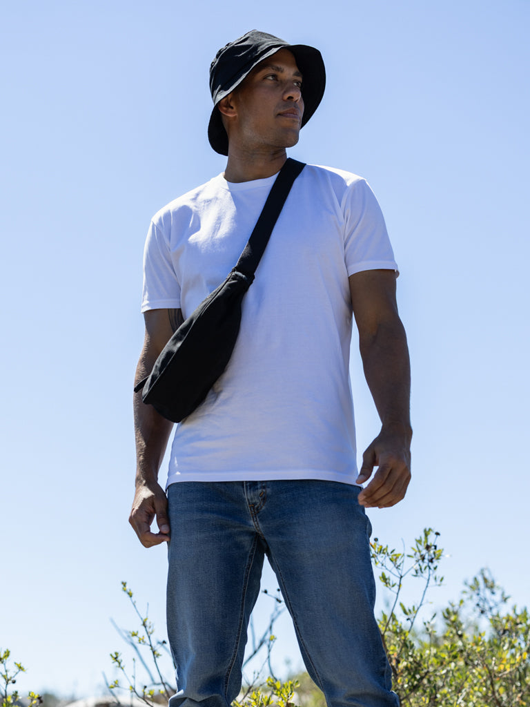 Man with a shoulder bag against a clear sky