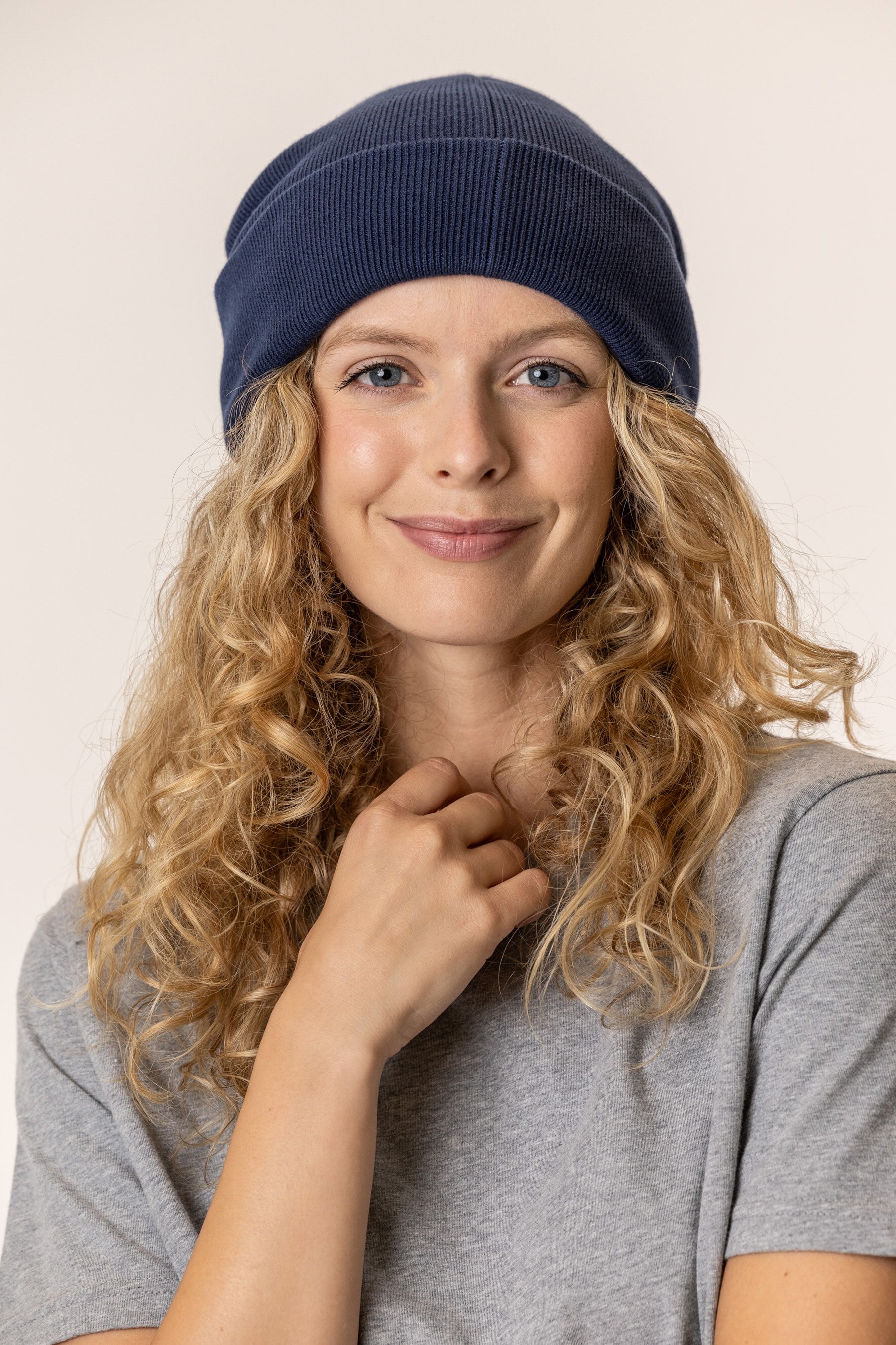 Woman wearing organic cotton navy blue beanie and heather gray t-shirt
