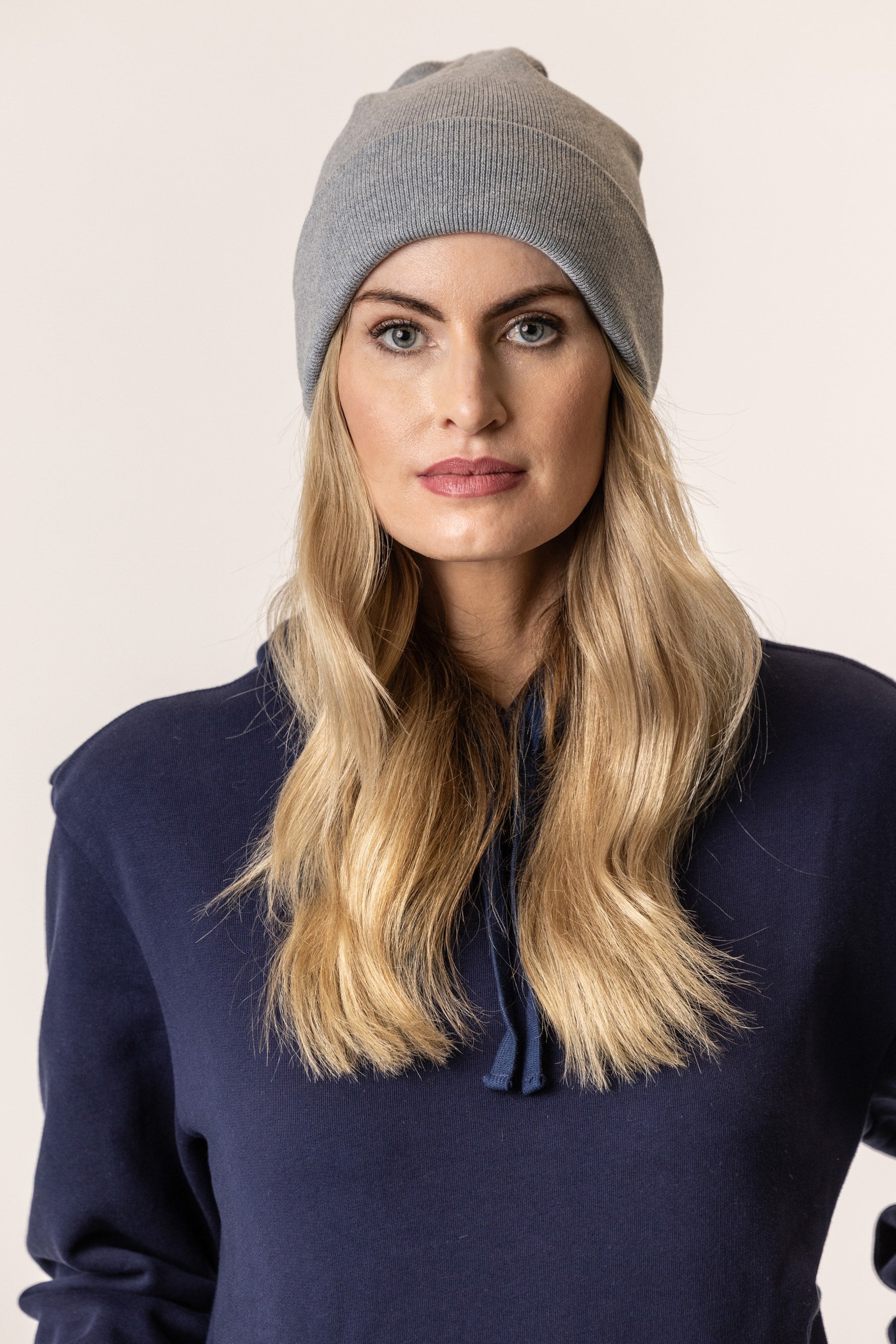 Woman wearing organic cotton gray beanie and navy blue hoodie