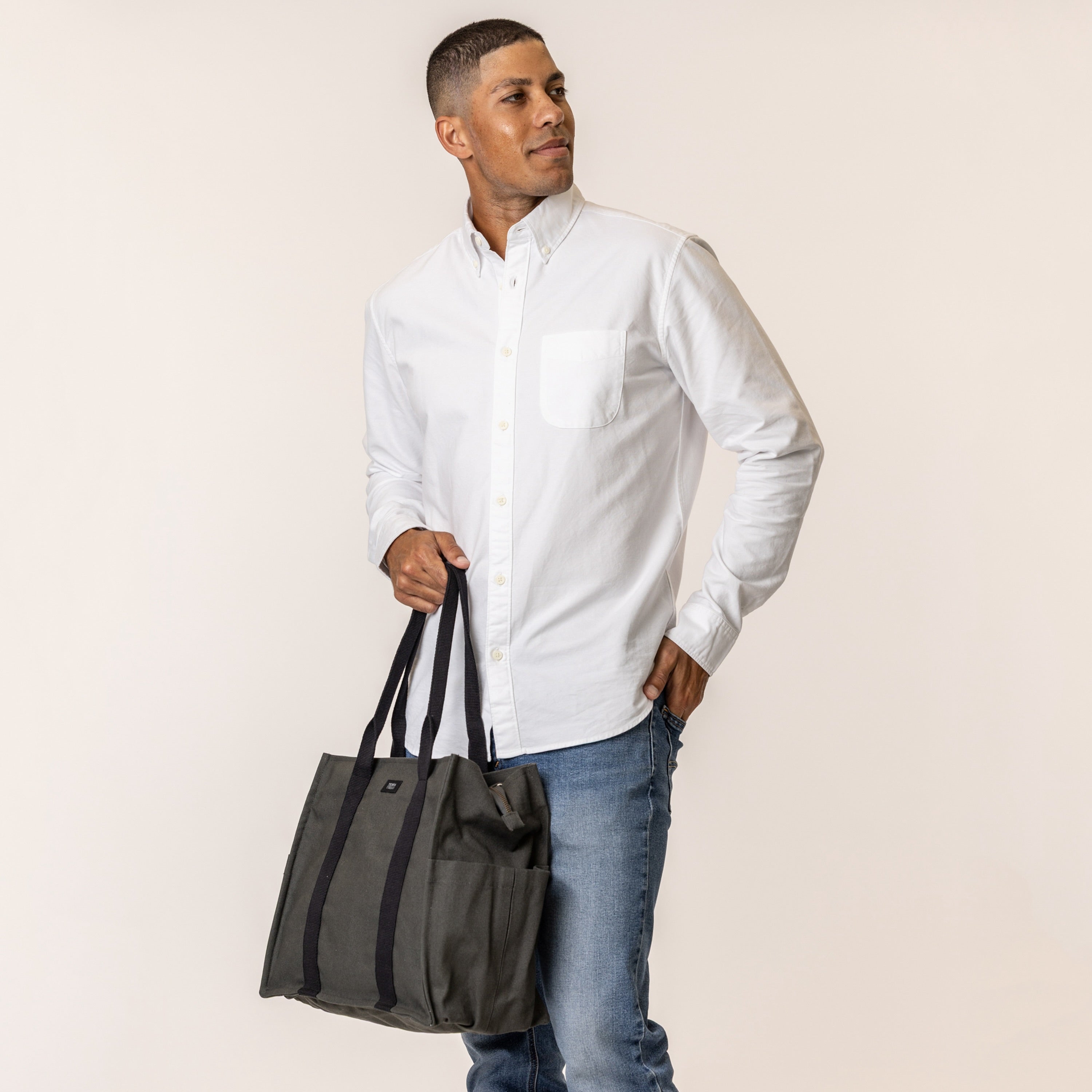 Man holding a sustainable handbag with pockets in charcoal grey color