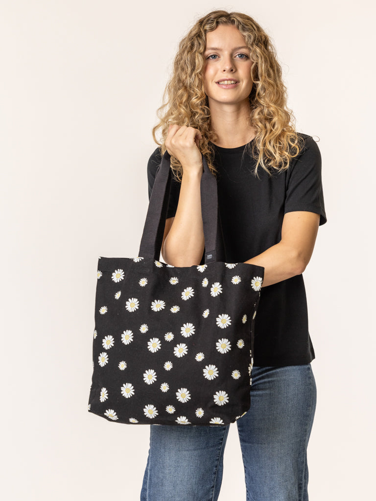 Woman holding a black tote bag with white floral pattern