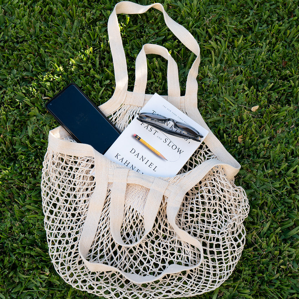 string produce bags with a book, phone and sunglasses inside