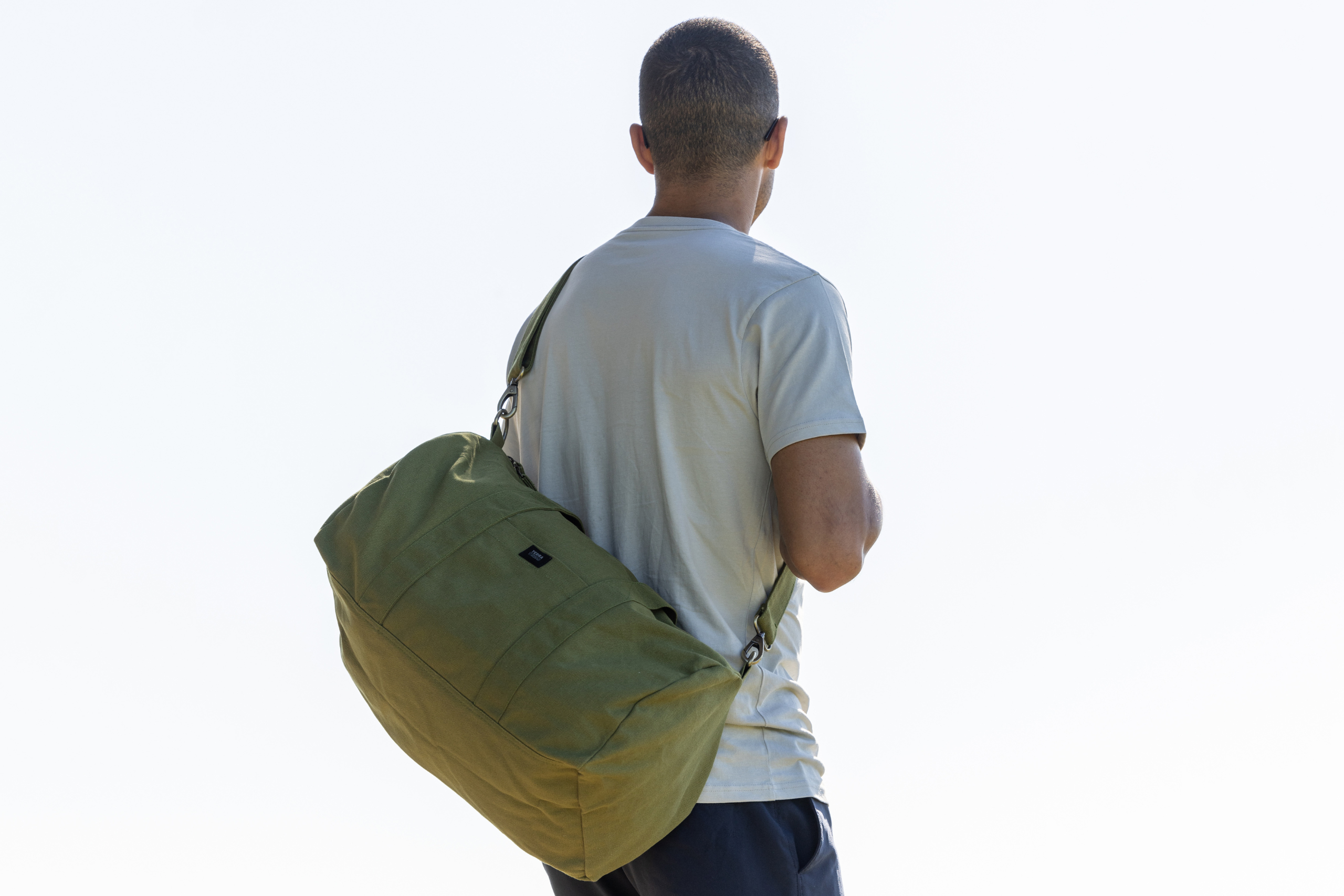 Model carrying Terra Thread organic cotton duffel bag in olive green color