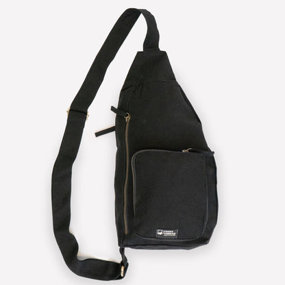A black canvas sling bag with a wide adjustable shoulder strap and front pockets
