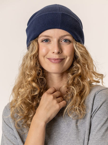 Woman wearing a navy blue beanie against a plain background