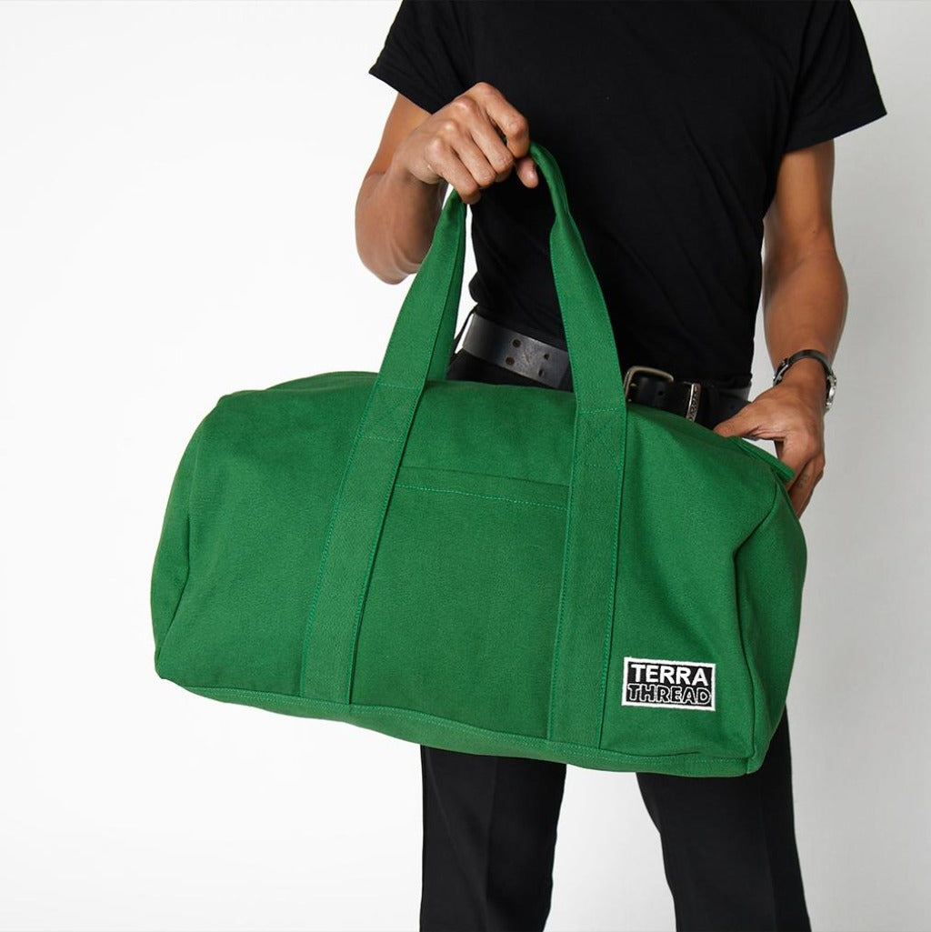 green duffle bag being held by a model